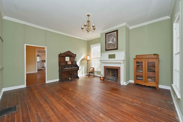 living room featuring an inviting chandelier, dark hardwood / wood-style floors, ornamental molding, and a fireplace