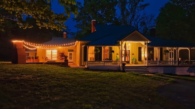 back house at twilight featuring a yard and a patio