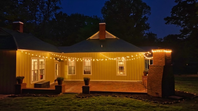 back house at night featuring a yard