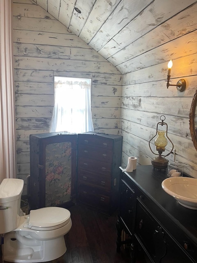 bathroom featuring toilet, hardwood / wood-style flooring, wooden walls, and vaulted ceiling