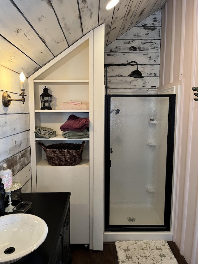 bathroom with vaulted ceiling, wooden ceiling, walk in shower, vanity, and wood walls