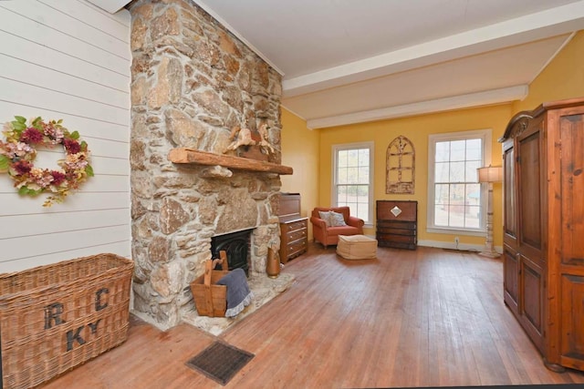 interior space with hardwood / wood-style flooring, beamed ceiling, wooden walls, and a fireplace