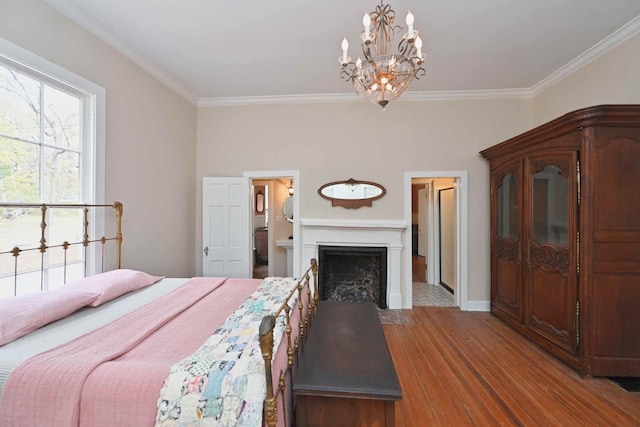 bedroom with hardwood / wood-style flooring, crown molding, an inviting chandelier, and ensuite bath