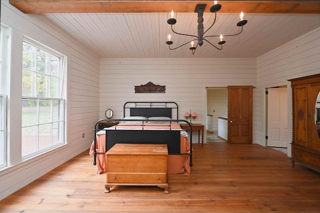 bedroom featuring beamed ceiling, light hardwood / wood-style flooring, wood walls, and a notable chandelier