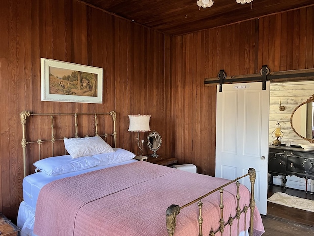 bedroom featuring a barn door, wood walls, and wooden ceiling