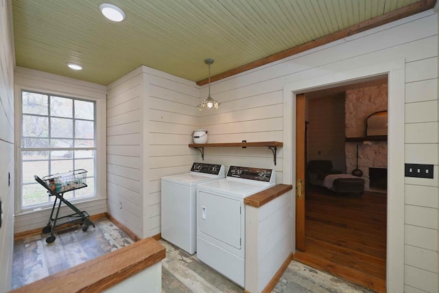 laundry room with wood walls, independent washer and dryer, and light wood-type flooring