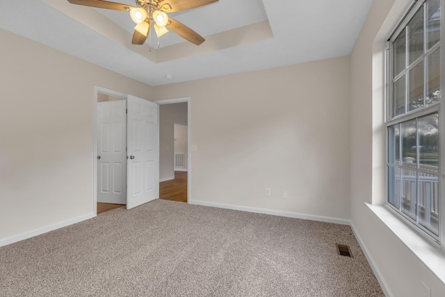 spare room featuring ceiling fan, carpet, and a tray ceiling