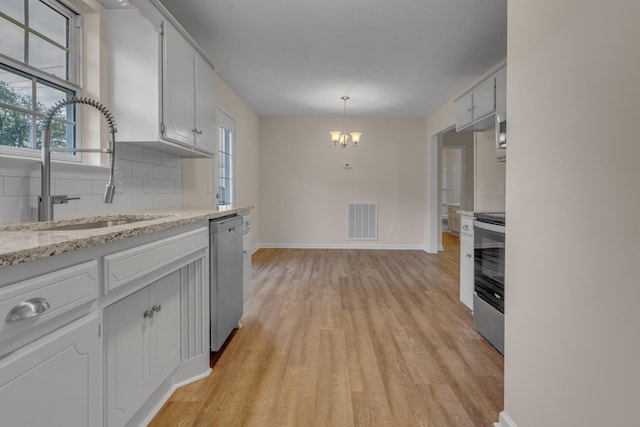 kitchen with pendant lighting, sink, white cabinetry, decorative backsplash, and stainless steel appliances