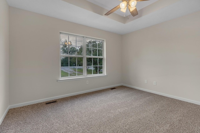 carpeted empty room featuring ceiling fan and a raised ceiling