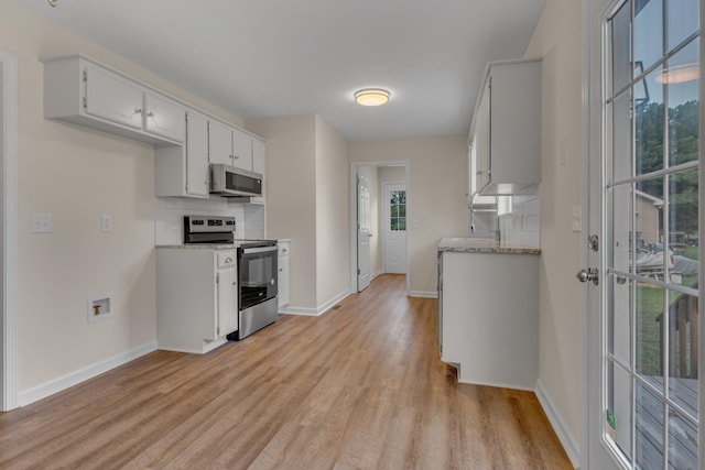 kitchen with appliances with stainless steel finishes, white cabinetry, decorative backsplash, plenty of natural light, and light wood-type flooring