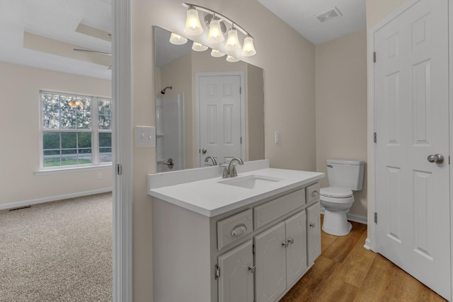 bathroom with vanity, a shower, toilet, hardwood / wood-style flooring, and a tray ceiling