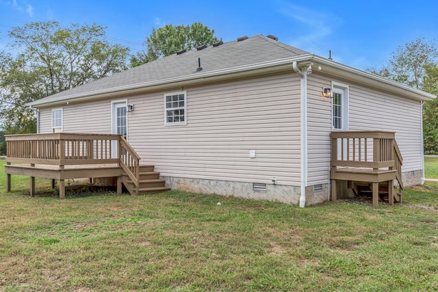 back of property featuring a wooden deck and a yard