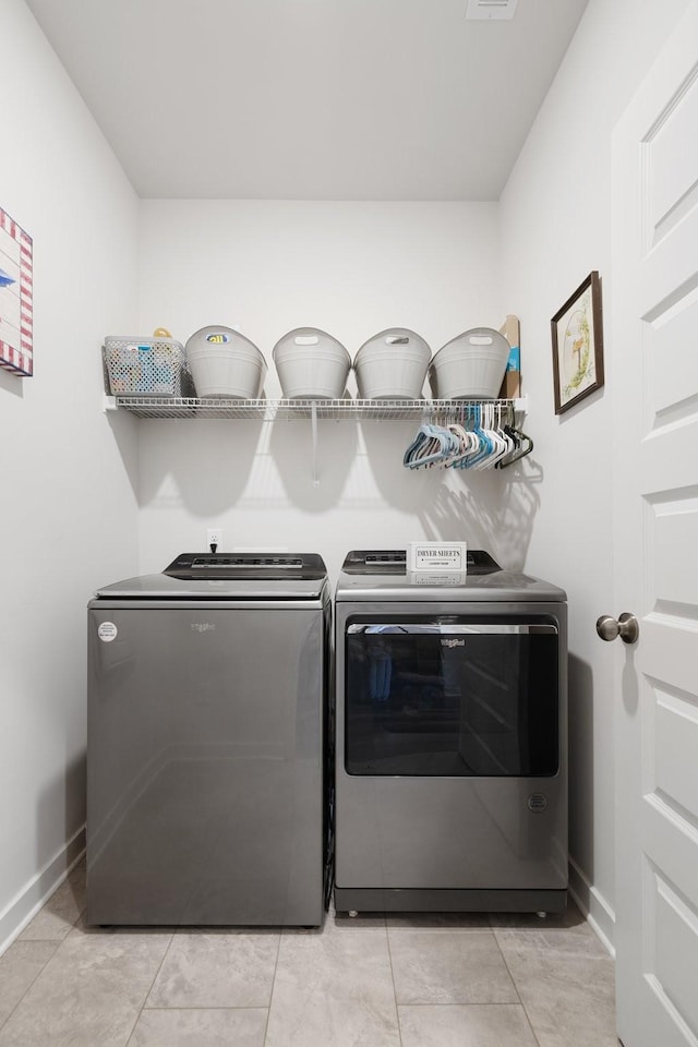 laundry area featuring washing machine and clothes dryer and light tile patterned floors