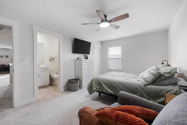 bedroom with ensuite bath, light colored carpet, and ceiling fan