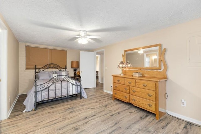 bedroom featuring light hardwood / wood-style floors, a textured ceiling, and ceiling fan