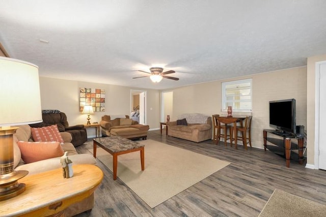 living room with a textured ceiling, ceiling fan, and dark hardwood / wood-style flooring