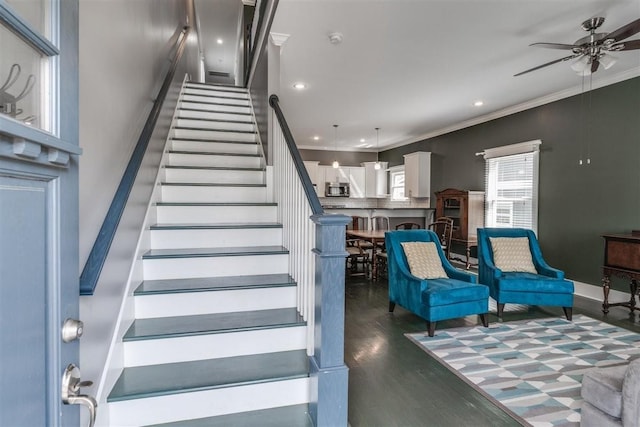 stairs featuring wood-type flooring, ceiling fan, and ornamental molding