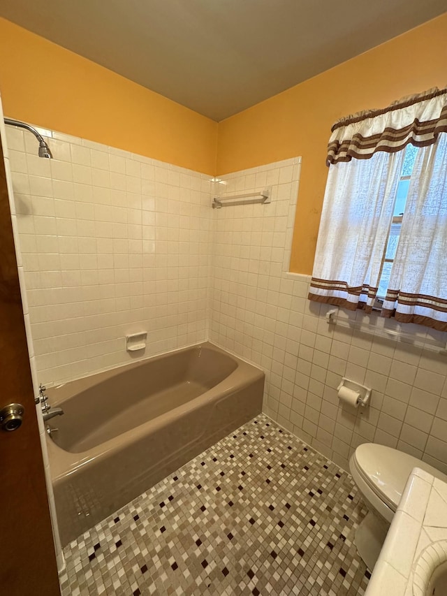 bathroom with shower / bathing tub combination, tile walls, tile patterned floors, and toilet