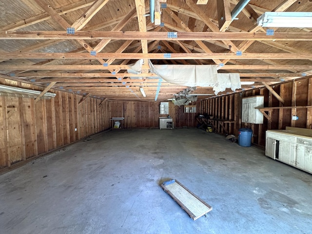 misc room with vaulted ceiling, concrete floors, and wood walls