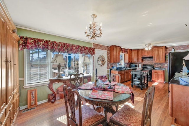 dining room featuring ceiling fan with notable chandelier and light hardwood / wood-style flooring