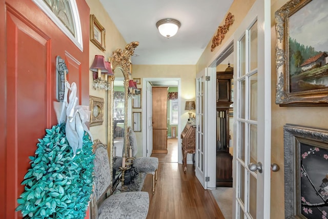 corridor with light hardwood / wood-style floors and french doors