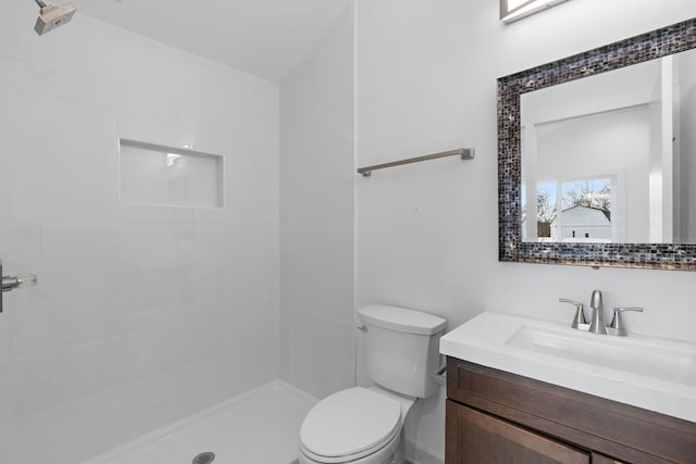 bathroom featuring vanity, toilet, and tiled shower