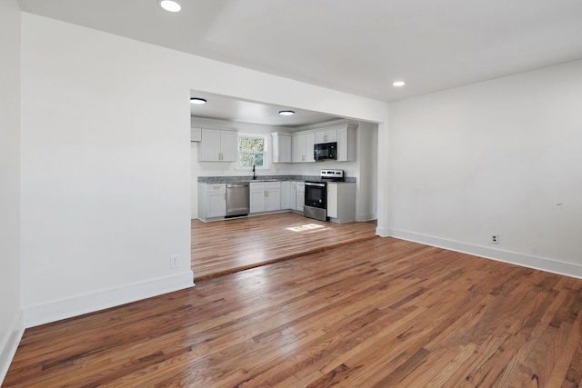 unfurnished living room featuring wood-type flooring and sink