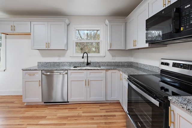 kitchen featuring appliances with stainless steel finishes, sink, white cabinets, and light wood-type flooring