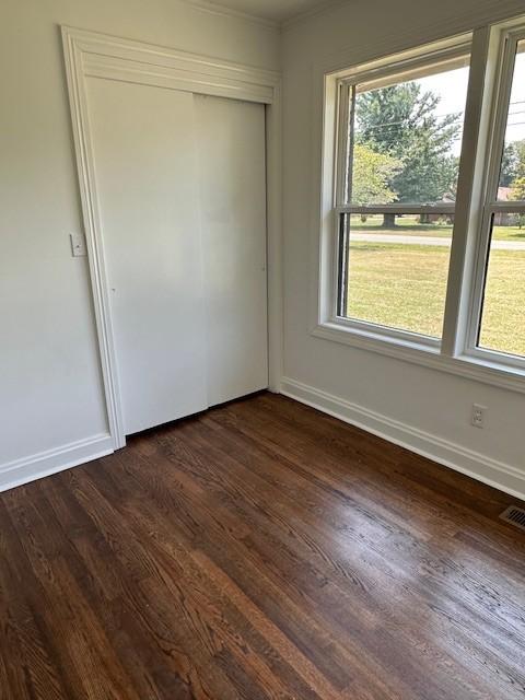 empty room featuring dark wood-type flooring and a healthy amount of sunlight