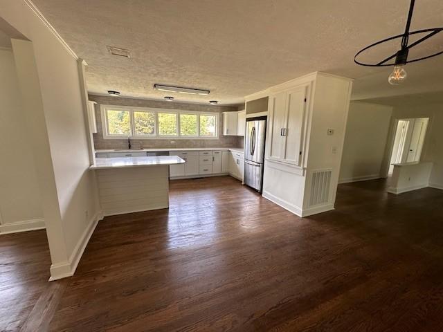 kitchen with white cabinets, a textured ceiling, stainless steel fridge, and dark hardwood / wood-style floors