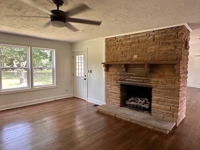 unfurnished living room featuring ceiling fan, a textured ceiling, dark hardwood / wood-style floors, and a stone fireplace