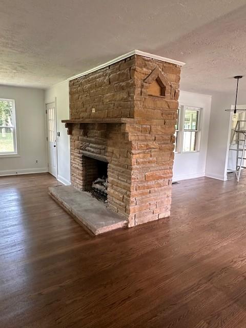 unfurnished living room with a healthy amount of sunlight, a textured ceiling, dark wood-type flooring, and a fireplace