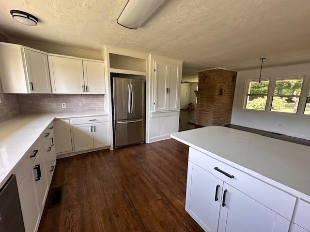 kitchen with decorative light fixtures, white cabinetry, and stainless steel refrigerator