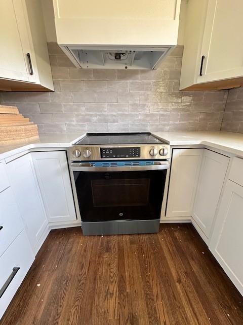 kitchen with decorative backsplash, dark wood-type flooring, white cabinetry, and stainless steel range with electric cooktop