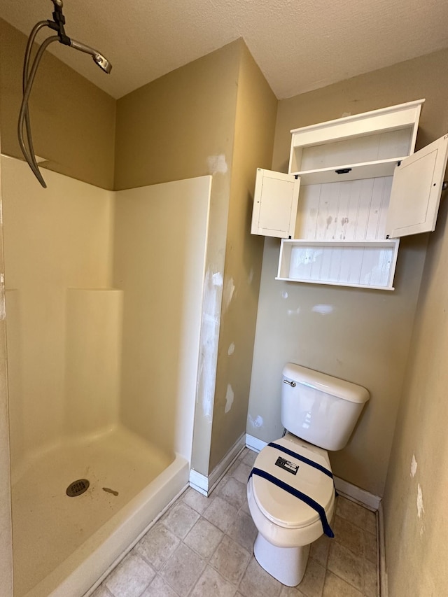 bathroom featuring a textured ceiling, toilet, and walk in shower