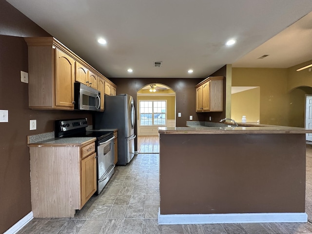 kitchen with kitchen peninsula, light brown cabinetry, ceiling fan, and stainless steel appliances