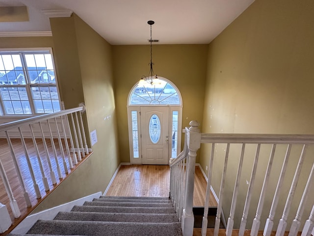 entrance foyer with crown molding, light wood-type flooring, and a notable chandelier