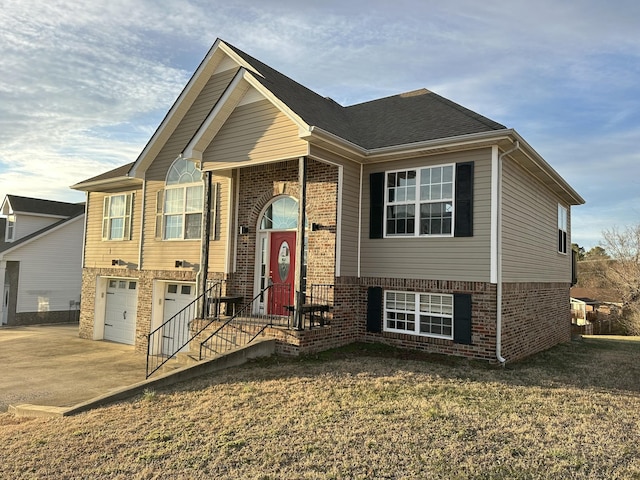 bi-level home featuring a garage and a front lawn