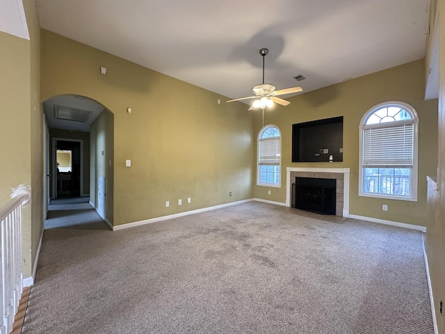 unfurnished living room with ceiling fan, carpet, and a tiled fireplace