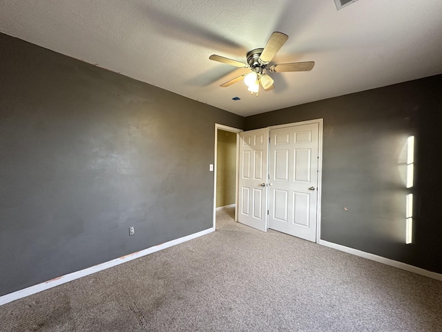 unfurnished bedroom featuring a closet, ceiling fan, carpet flooring, and a textured ceiling