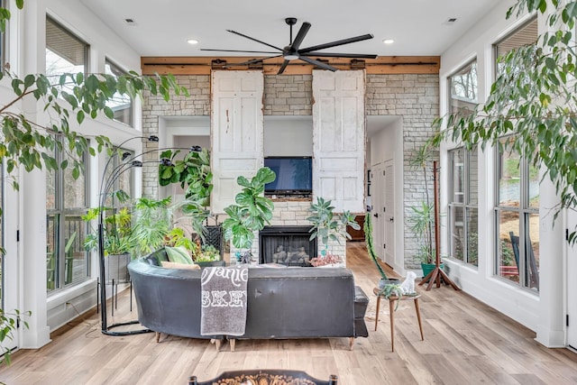 living room featuring ceiling fan, light hardwood / wood-style flooring, and a fireplace