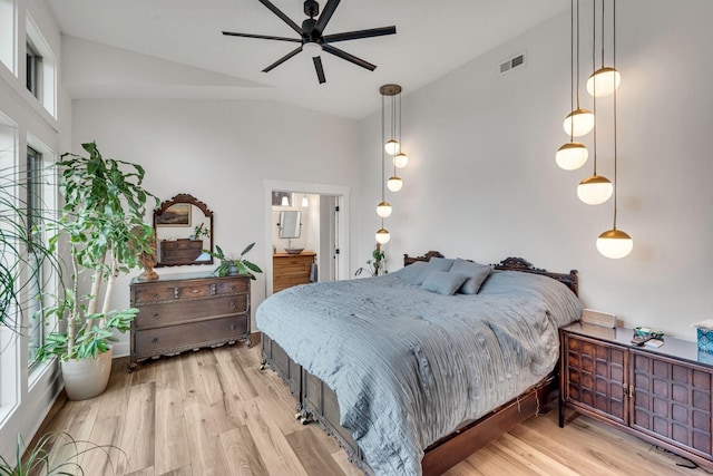 bedroom featuring light wood-type flooring, vaulted ceiling, ceiling fan, and ensuite bath