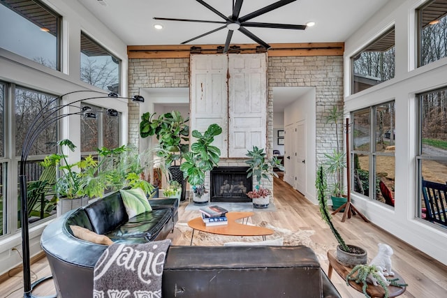 sunroom featuring ceiling fan and a fireplace