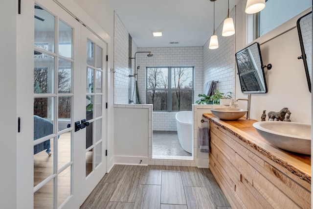 bathroom featuring plus walk in shower, vanity, and french doors