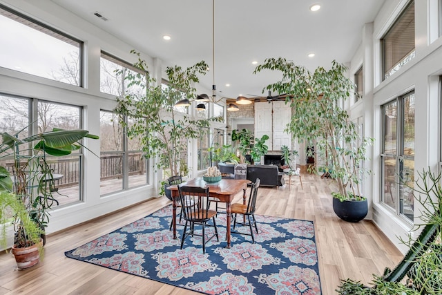 dining room with a high ceiling, light wood-type flooring, and a healthy amount of sunlight