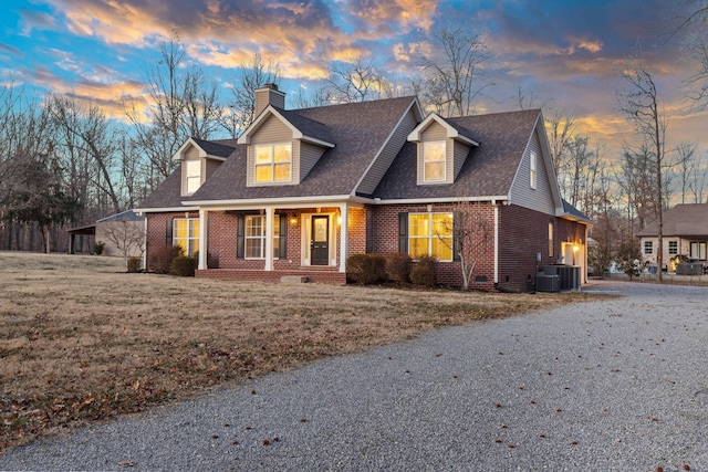 new england style home featuring a garage, cooling unit, a yard, and a porch