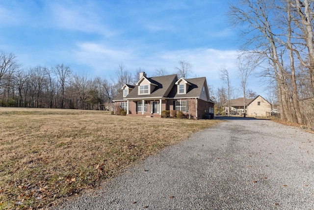 cape cod home with covered porch and a front lawn