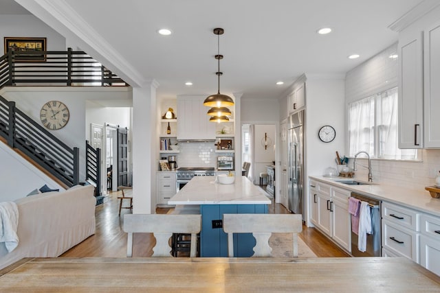 kitchen with pendant lighting, appliances with stainless steel finishes, sink, white cabinets, and a kitchen island