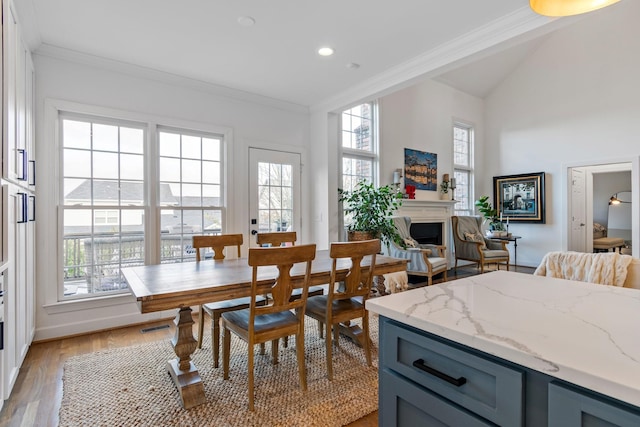 dining room with light hardwood / wood-style flooring, lofted ceiling, and ornamental molding