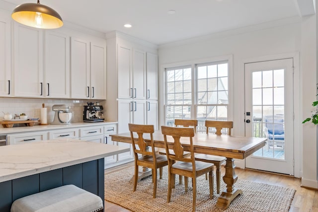 dining room with light hardwood / wood-style floors, crown molding, and a healthy amount of sunlight